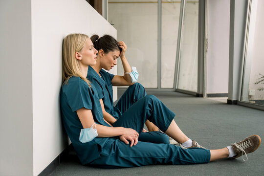 Nurses sitting on hospital floor appearing tired and exhausted
