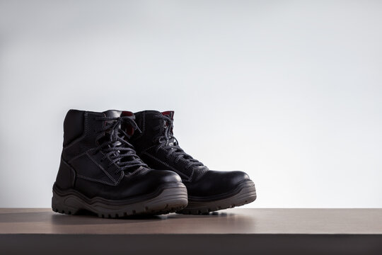  black work boots on a wooden shelf. place for text.