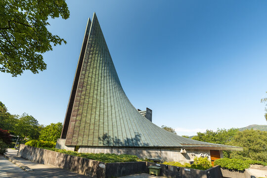 View of modern Slettebakken Church with a steep, triangular roof reaching for the sky, contrasting with the lush greenery surrounding it, Bergen, Vestland, Norway.