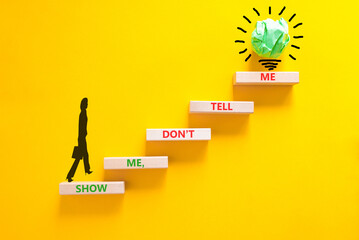 Tell or show symbol. Concept words Show me, do not tell me on beautiful wooden blocks. Beautiful yellow paper background. Light bulb icon. Businesswoman icon. Business tell or show concept. Copy space