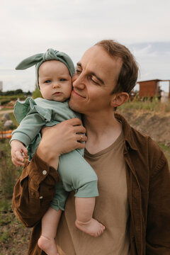Father holding baby girl outdoors showing gentle parenting and attachment