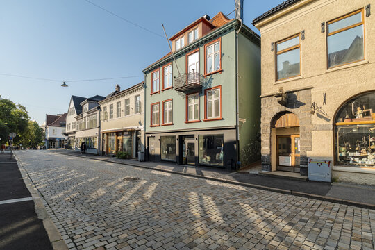 View of old buildings line the cobblestone street, casting long shadows in the warm sunlight, Bergen, Vestland, Norway.