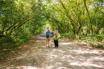 Fototapeta premium Senior Couple Enjoying a Walk and Conversation on a Sunlit Green Forest Path