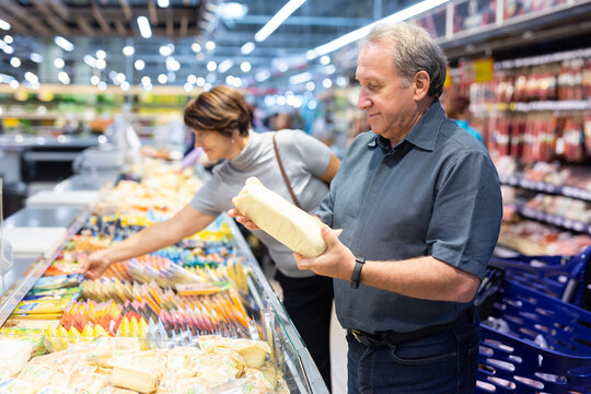 Elderly man choose cheese in supermarket