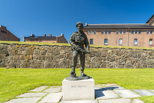 View of bronze statue of Max Manus stands proudly on a stone pedestal amidst the vibrant green lawn and ancient stone walls, Oslo, Oslo, Norway.