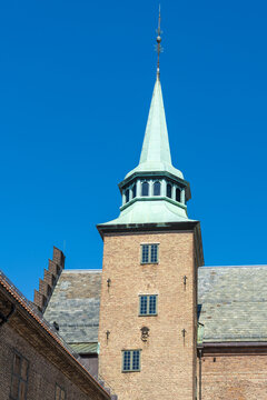 View of a brick tower with a green spire under a clear blue sky, a majestic landmark piercing the skyline, Oslo, Oslo, Norway.