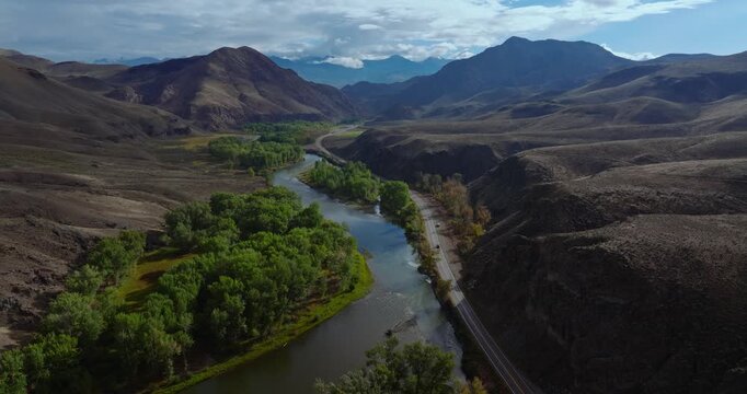 Highway 93 tracing river through wide Idaho valley under blue sky