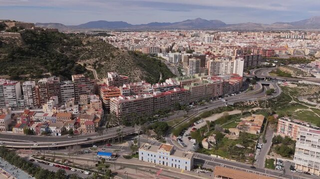 Drone footage of Alicante city with Serra Grossa hills, highways and dense urban skyline. Mediterranean coastal city landscape on the Costa Blanca in Spain.