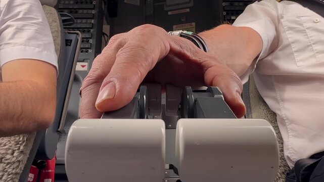 Extreme low angle, close-up view of the hand of a pilot adjusting the throttle levers in a real time flight and doing routine procedures.