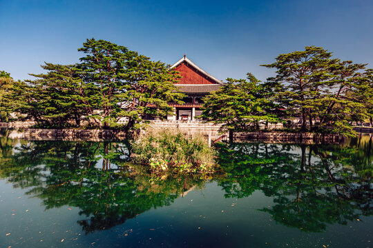 View of the building with red roof reflected in the water with green trees around, capturing the essence of history and nature, Seoul, Seoul, South Korea.