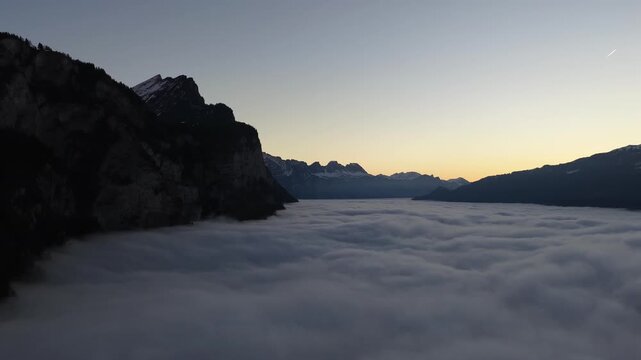 Aerial sunrise above dense clouds over Walensee surrounded by dramatic alpine mountains and serene Swiss landscape.