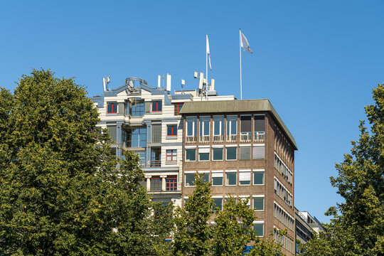 View of modern architecture contrasts lush greenery under a brilliant blue sky, flags fluttering atop the buildings, Oslo, Oslo, Norway.
