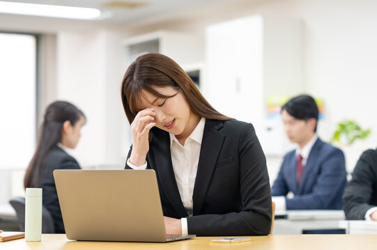 仕事中に頭痛や疲れを感じて悩むビジネスパーソン　オフィス・残業・ストレス