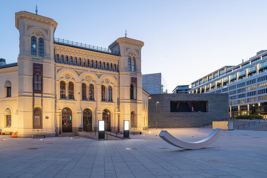 View of illuminated facade of noble peace prize museum building with ornate details and symmetrical towers standing proudly on a spacious square, Oslo, Oslo, Norway.