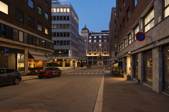 View of a quiet street illuminated by the soft glow of building lights contrasting with the deepening twilight sky, Oslo, Oslo, Norway.