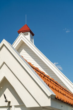 View of white walls rise to meet a red-tiled roof under a brilliant blue sky, a simple yet striking architectural contrast, Oslo, Oslo, Norway.