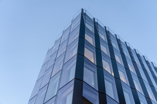 View of a modern architectural marvel with a geometric facade of glass and steel reaching towards a serene blue sky, Oslo, Oslo, Norway.