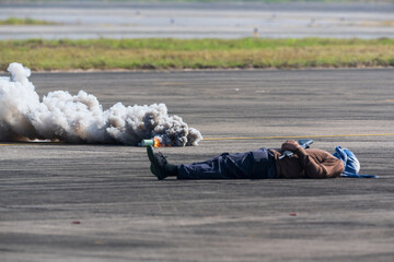 Naklejka premium Selective smoke from smoke bomb and out of focus terrorist lies dead during military assault drill.The criminal was killed by riot police.A drill simulating a rescue operation against terrorists conce