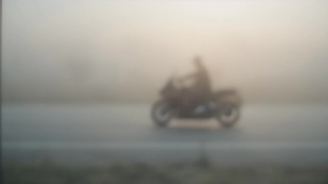 A light-colored vehicle navigates a road shrouded in thick fog