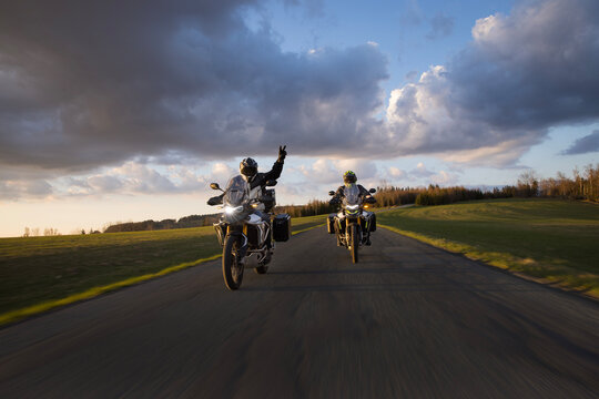 Drivers riding motorcycle on empty road during sunset, spring mountains