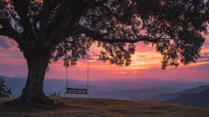 Wide sunset view with swing beneath giant tree silhouette against glowing evening sky