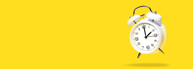 White bell alarm clock hovering over yellow background. 2 to 3 clock concept isolated. daylight...