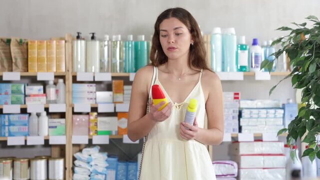 Young woman in summer dress choosing insect and mosquito repellents at pharmacy. Buying mosquito protection in the summer. High quality 4k footage
