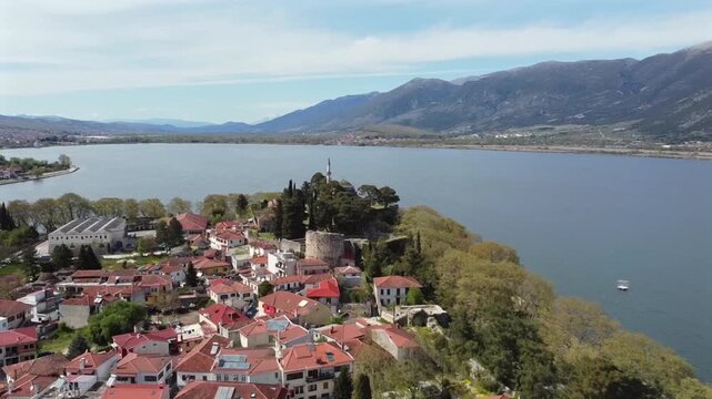 Drone camera flying straight towards the historic Aslan Pasha Mosque on the cliffside of Ioannina Castle in Greece with the scenic Lake Pamvotida and mountains in the background