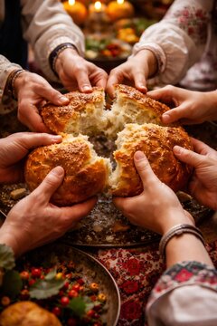 Many hands reaching to break and share a round, homemade bread, symbolizing unity, communion, and hospitality around a table set for a celebration or gathering