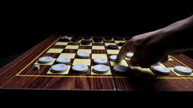 Hand making a tactical move on a classic checkers board game