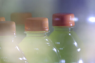 Dreamy blurry and hazy view of green juice bottles. cold refreshment drink in refrigerator offers...