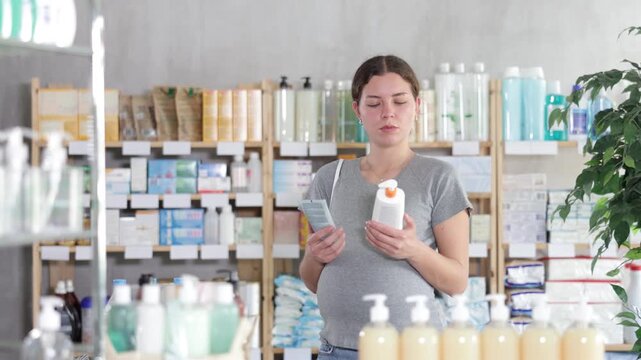 Smiling pregnant woman choosing creams and lotions to moisturize her skin. Woman shopping at pharmacy during pregnancy. High quality 4k footage