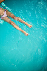Teen girl enjoying a relaxing swim on a sunny summer day in a vibrant pool