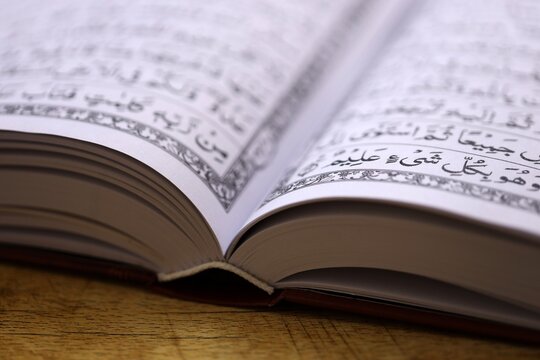 Pages of Al Quran Muslim holy book on table in mosque. Details of arabic calligraphy in islamic book. Concept of Islam religion and praying in arabic countries