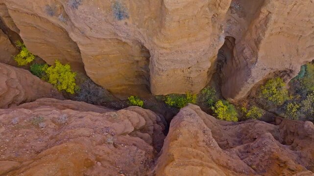 Directly above drone view captures narrow eroded sandstone combe in Konorchek canyons. Rugged terrain showcases stunning natural formations under daytime sky.