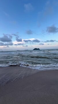 Cinematic view of ocean waves and scenic coastline at Samila Beach during sunset in Songkhla, Thailand.