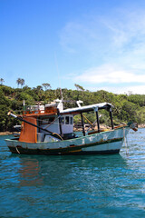 Obraz premium Colorful Fishing Boat Floating on Clear Blue Tropical Water with Green Island Hills