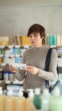 Woman in autumn clothes buys medicinal ointment at a pharmacy. High quality 4k footage