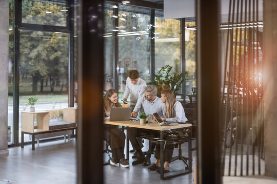 Business office with people casual wear, with blurred bokeh background, view from glass wall.