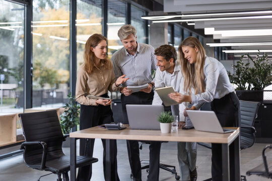 Group of young modern people in formalwear using modern technologies while working in the creative office.