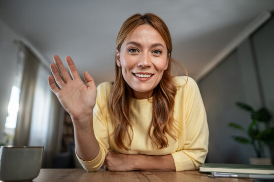Woman waving hello connecting on video call from home