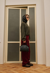 Fototapeta premium Stylish woman with handbag in elegant outfit posing indoors