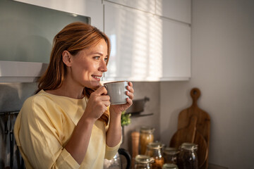 Woman enjoying morning coffee in kitchen sunlight