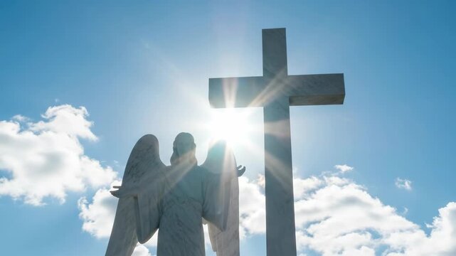 Angel statue standing next to christian cross against a bright sun in blue sky. Religious scene capturing spiritual faith and divine light in a peaceful nature.