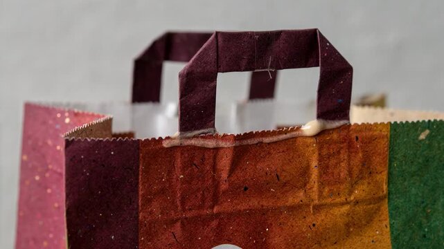Closeup of flat handle attachment on a vibrant dyed paper bag showcasing precision gluing techniques and colorful material contrast in sustainable bag production.