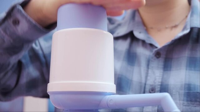 Woman using manual water pump at home pouring clean drinking water promoting healthy lifestyle and hydration concept