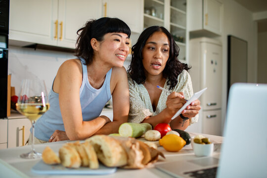 Two friends cooking and meal planning in a home kitchen