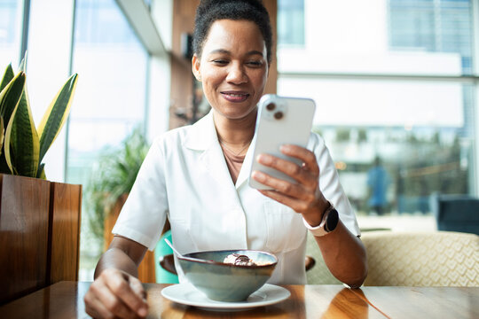 Smiling woman using smartphone at cafe table