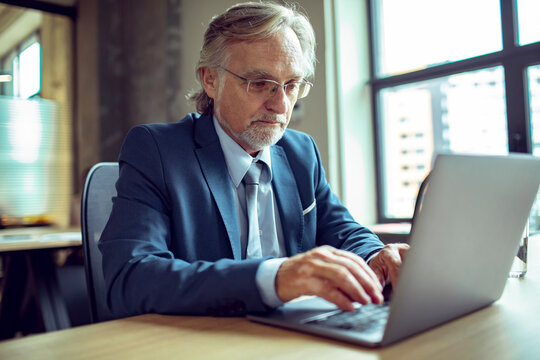 Senior businessman working on laptop in modern office