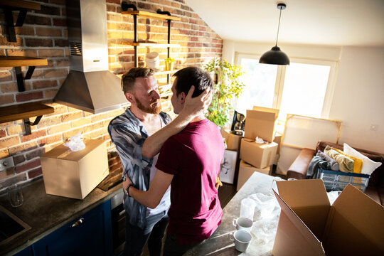 Two men hugging while unpacking in a new kitchen